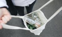 En person holder et net med flasker til genbrug